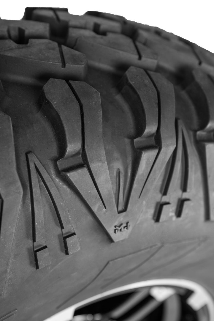 Close-up of a black tire tread featuring intricate patterns and the embossed word "awat," viewed in a monochrome tone.
